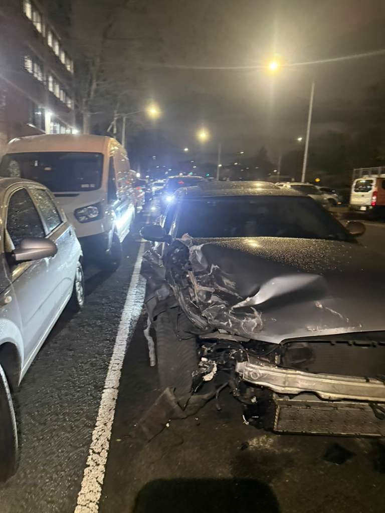 Sedan with heavy front-end crash damage recovered on a Queens street at night — JG Towing.