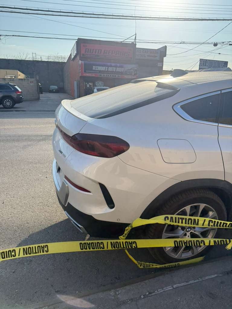 White BMW X6 cordoned off with caution tape after an incident on a Queens avenue — JG Towing.