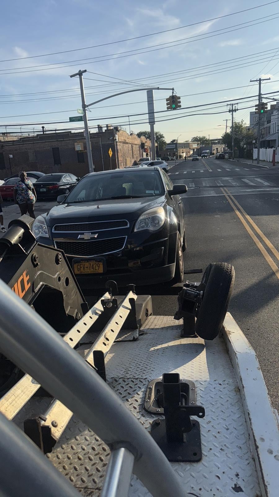 Chevy Equinox on JG Towing wheel-lift truck on a Queens commercial avenue.