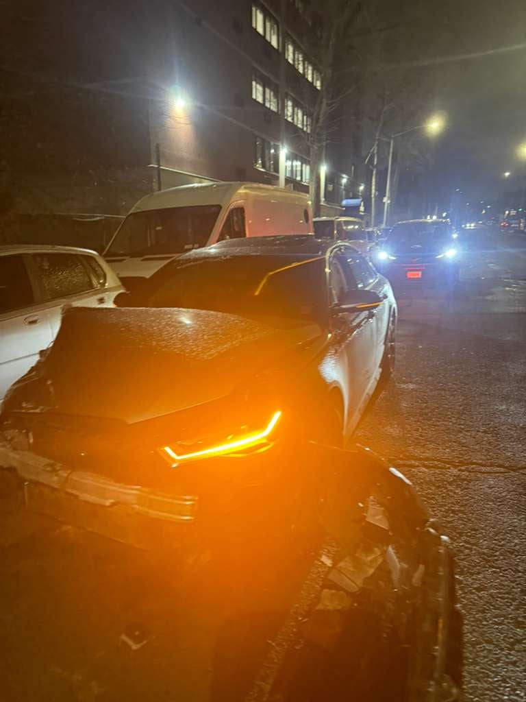 Damaged Dodge Charger with DRL lit during a night recovery by JG Towing in Queens.