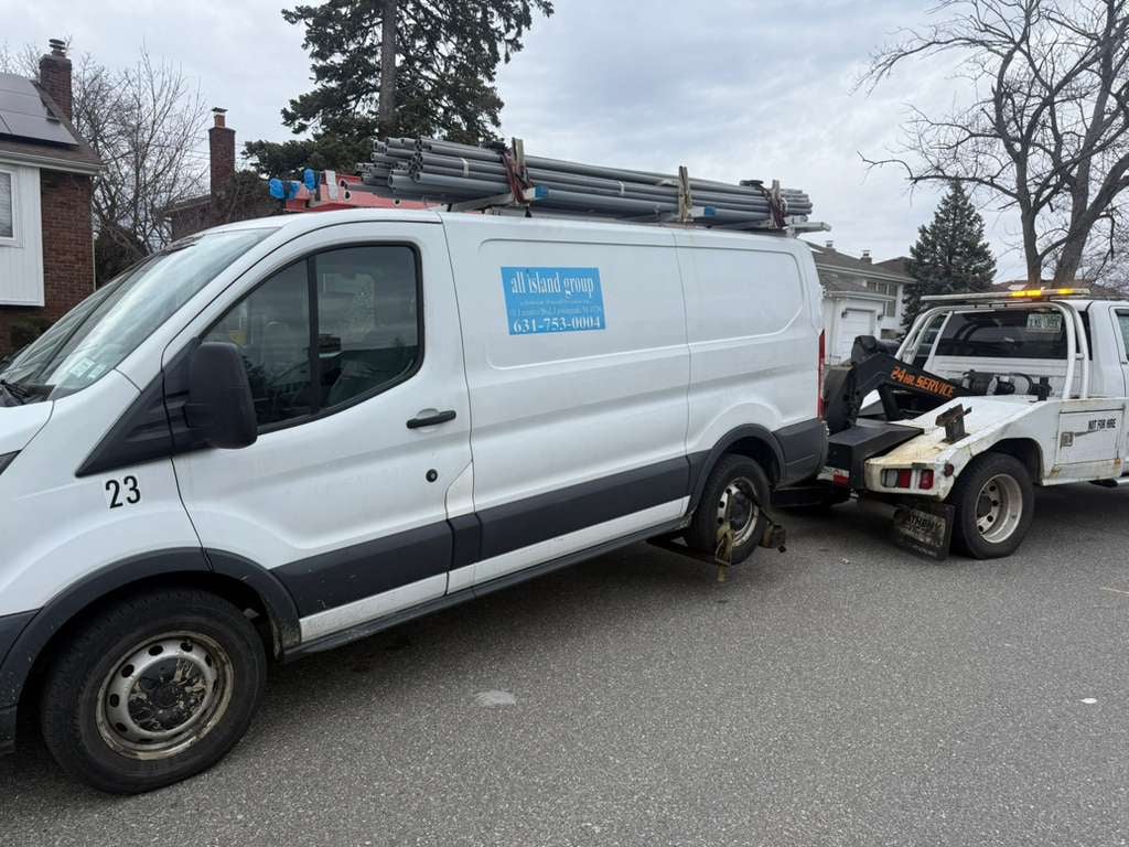 White Ford Transit work van on JG Towing wheel-lift after a breakdown in Queens.