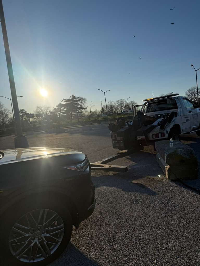 Same Acura MDX from the accident recovery loaded on JG Towing wrecker for the long-distance haul out of Flushing Meadows-Corona Park, Queens, at sunset.