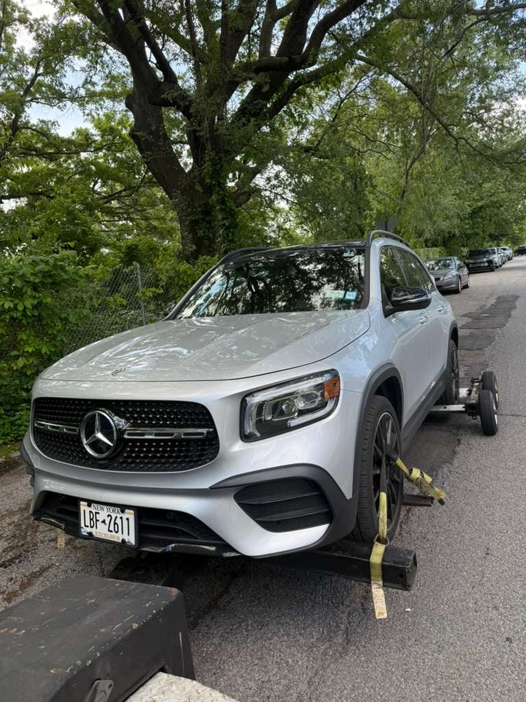Silver Mercedes-Benz GLB on JG Towing wheel-lift under shade trees.